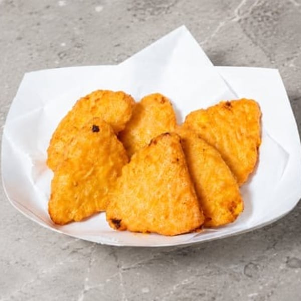 Golden-brown hash browns served in a white paper tray on a gray countertop.