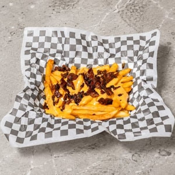 Cheesy bacon fries in a black and white checkered paper tray.